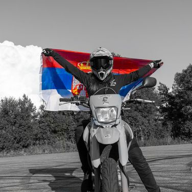 Person holder opp et flagg, sittende på motorsykkel